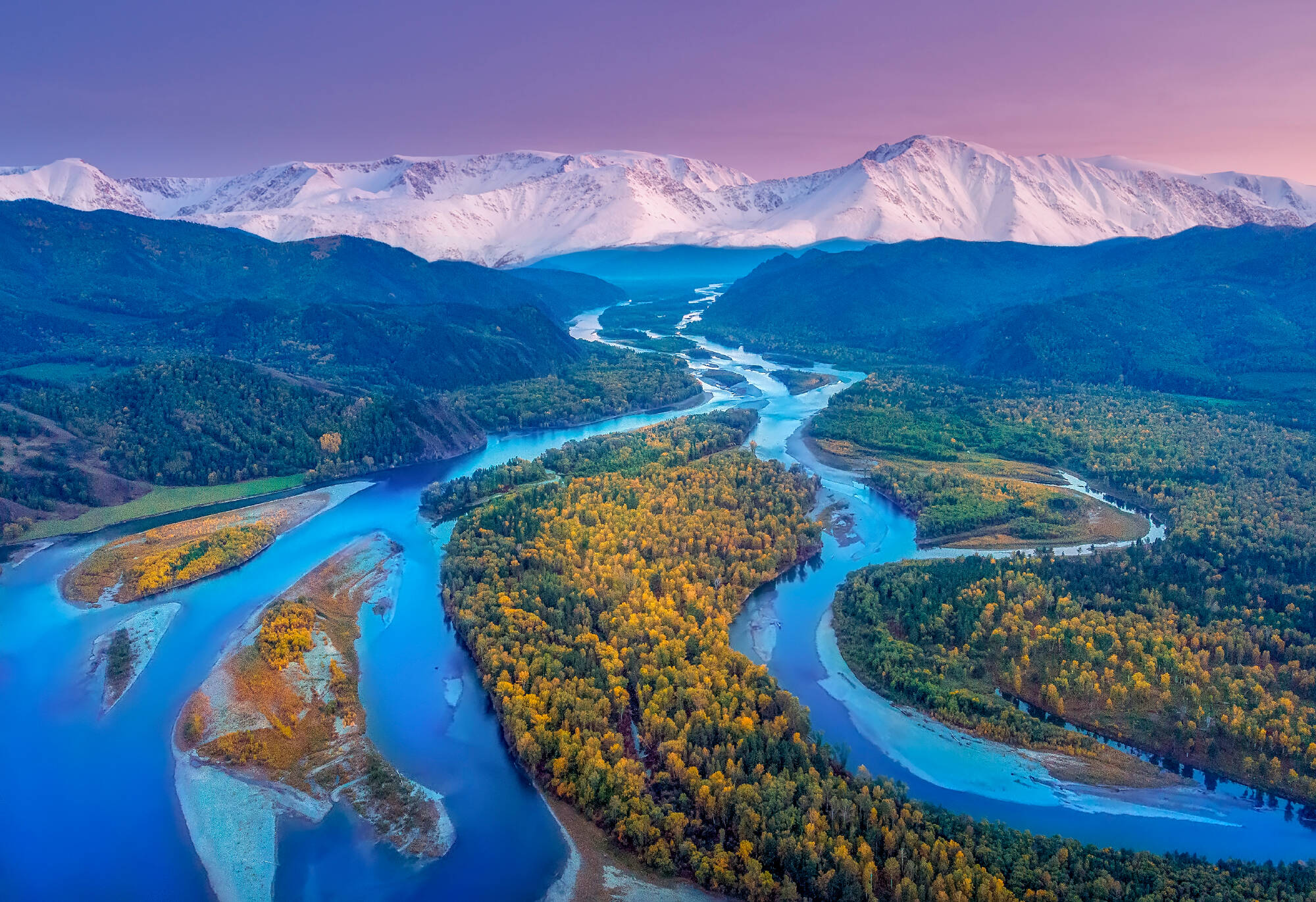 Herbstsicht auf das Flussbett mit Schatten von gelben Bäumen nach Sonnenuntergang auf dem Hintergrund der hohen Berge, der Abakan Fluss in Chakassia