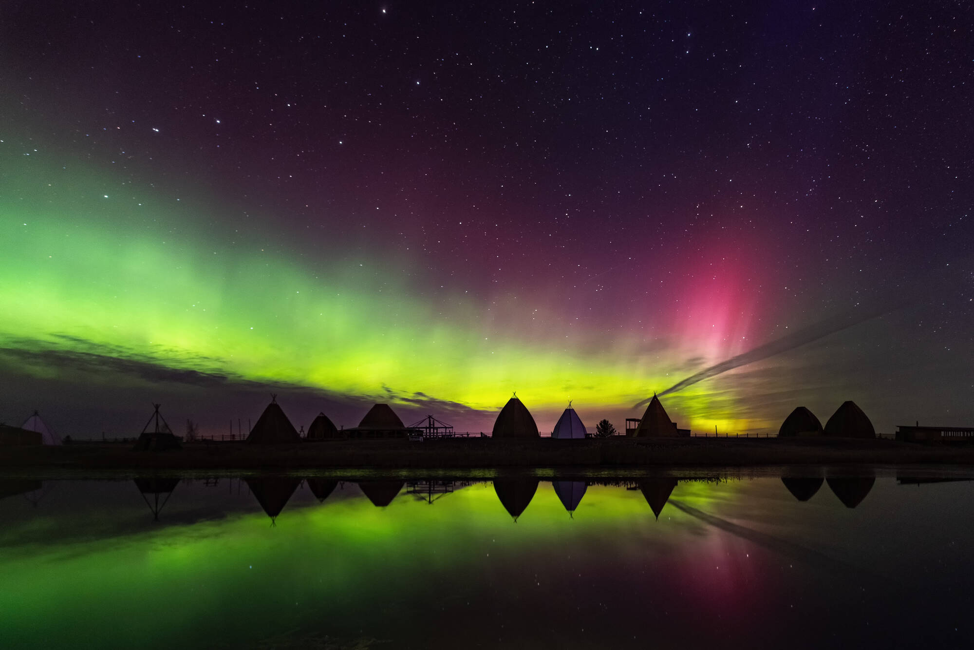 Aurora borealis in Jakutsk, Jakutien, Russland. Aurora. Grüne und rote Nordlichter. Sternenhimmel mit Polarlichtern. Nachtlandschaft mit Jurururten unter Aurora Borealis, See mit Himmelsreflektion 