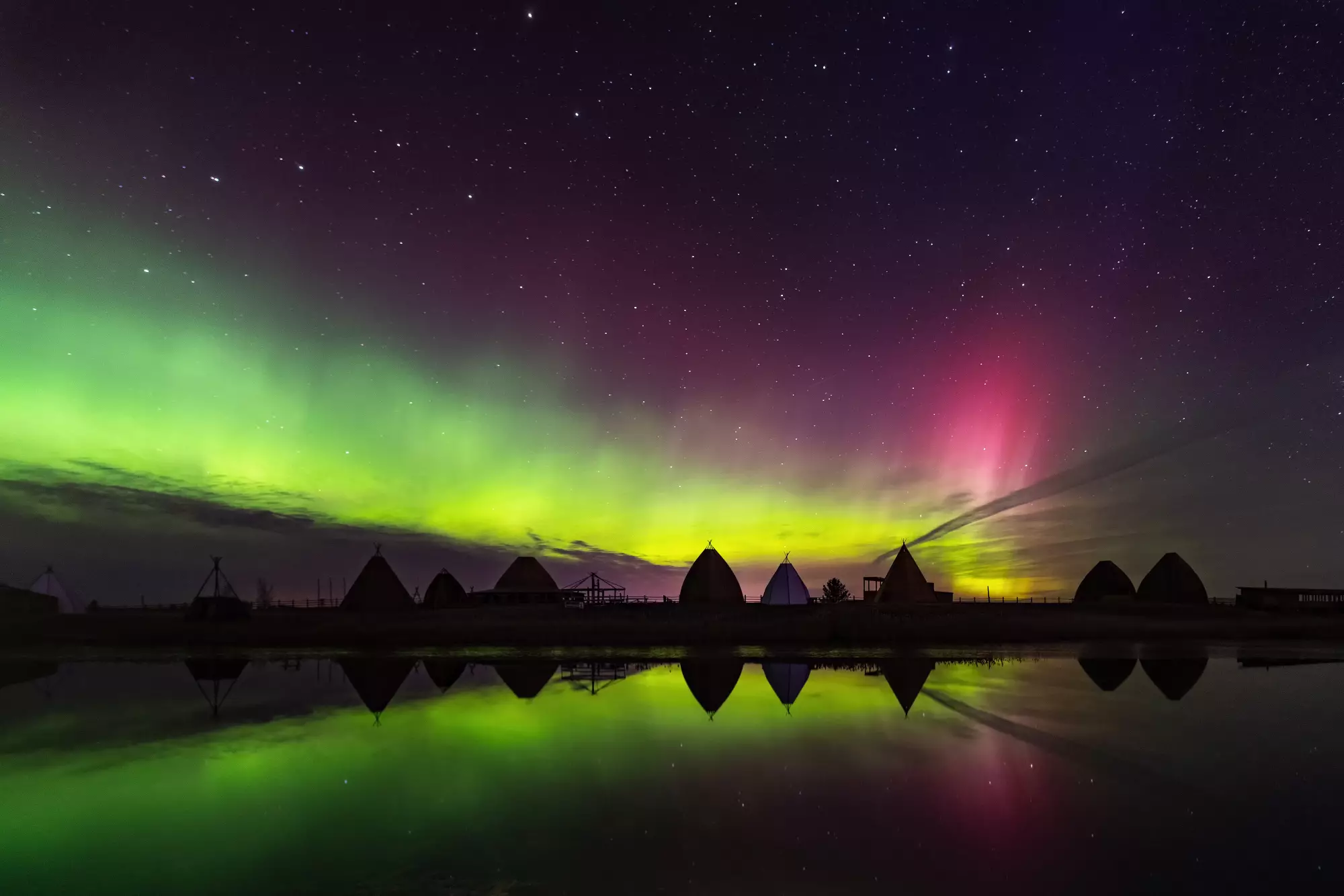 Aurora borealis in Jakutsk, Jakutien, Russland. Aurora. Grüne und rote Nordlichter. Sternenhimmel mit Polarlichtern. Nachtlandschaft mit Jurururten unter Aurora Borealis, See mit Himmelsreflektion 